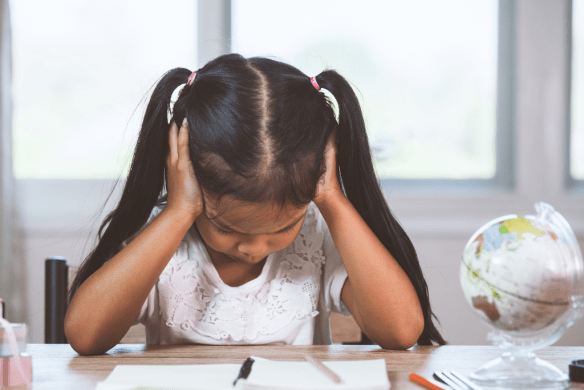 Young child feeling overwhelmed by schoolwork, illustrating how anxiety and academic pressure can affect focus, concentration, and emotional wellbeing.